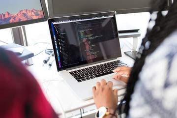 Photo of computer and Black female student coding