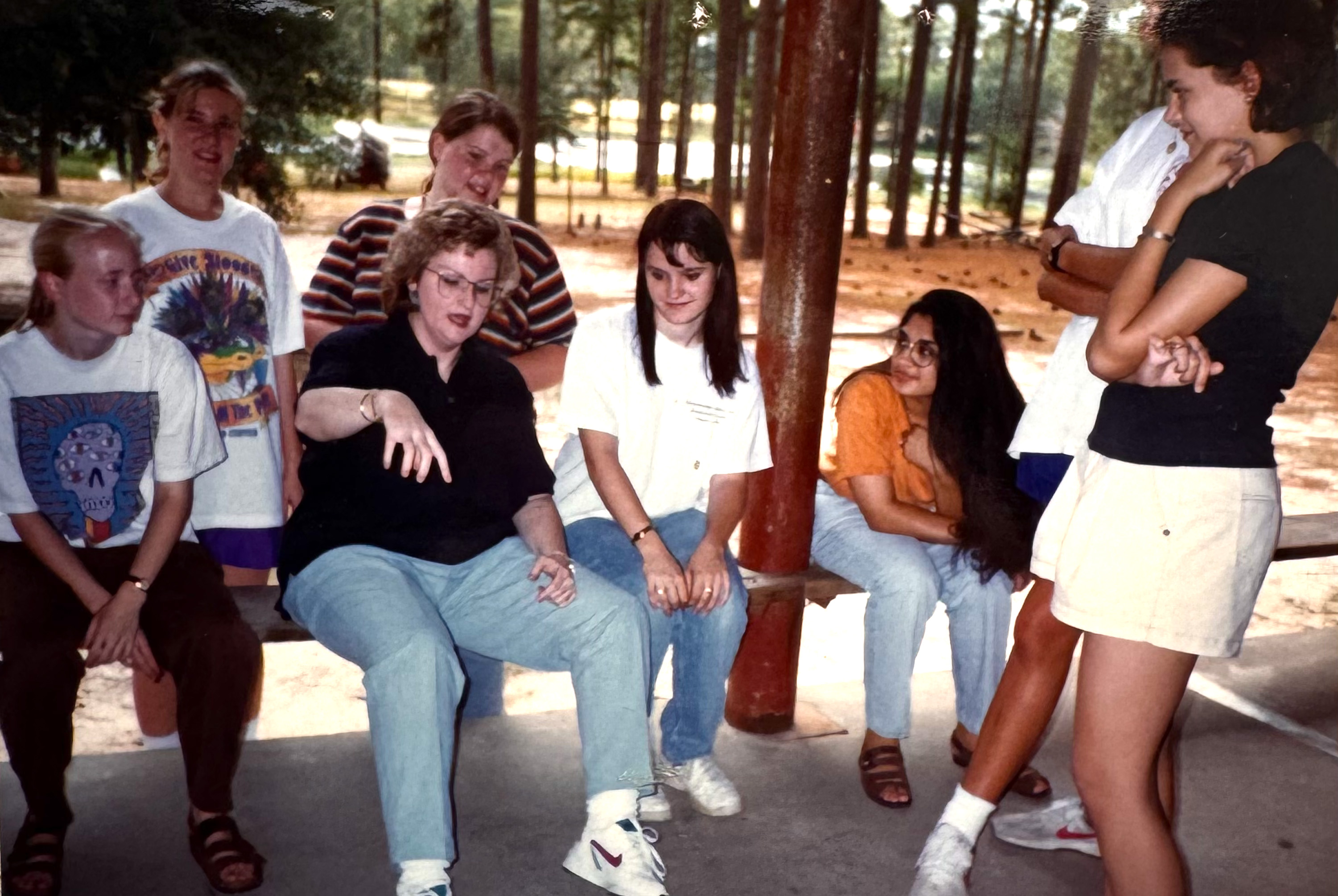 Students sitting on a bench on campus listening to a professor