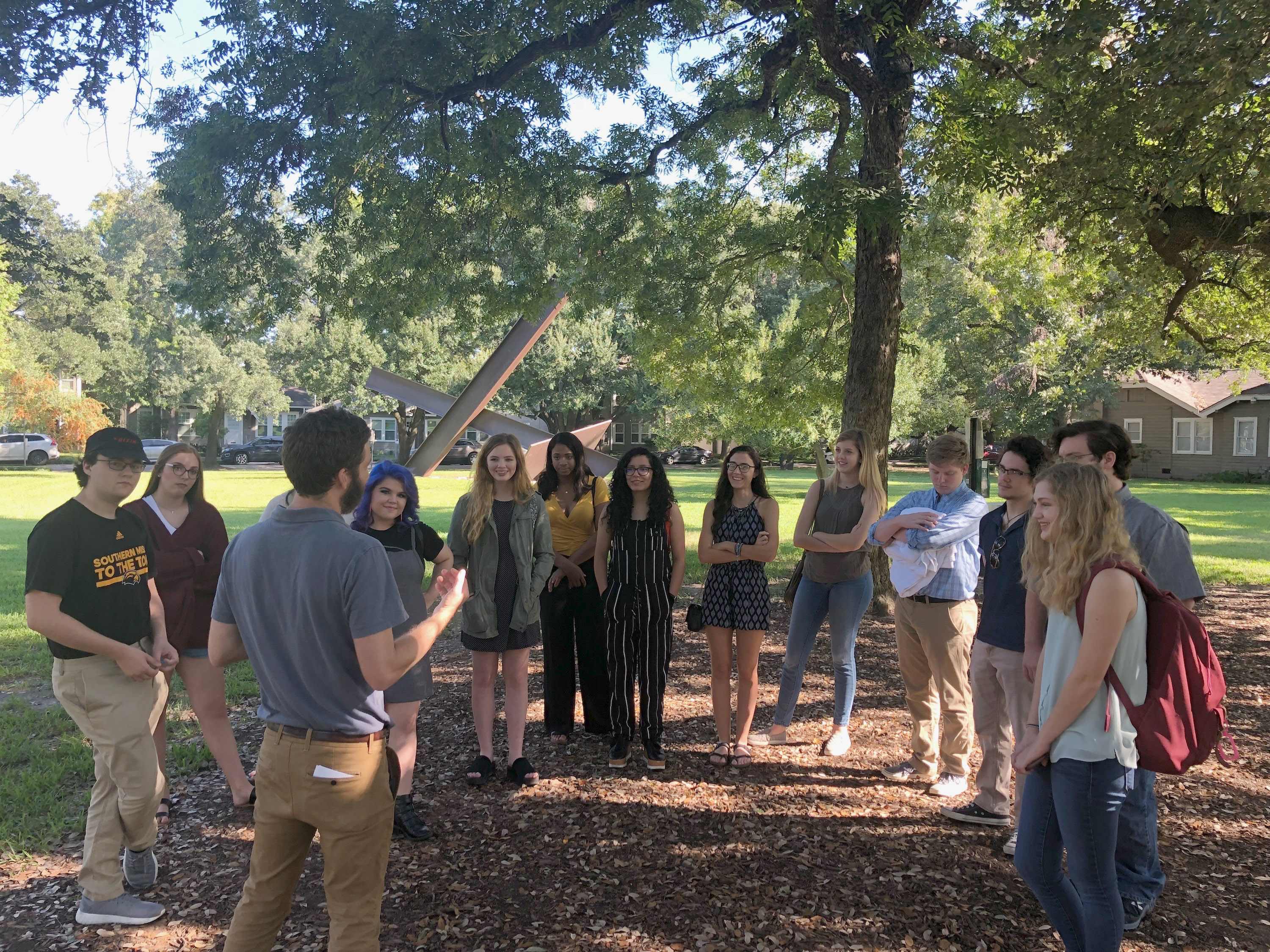 Students in a class being held outside under a tree