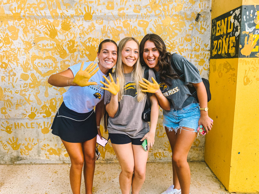 Three female students with gold hands at the painting of eagle walk event. 