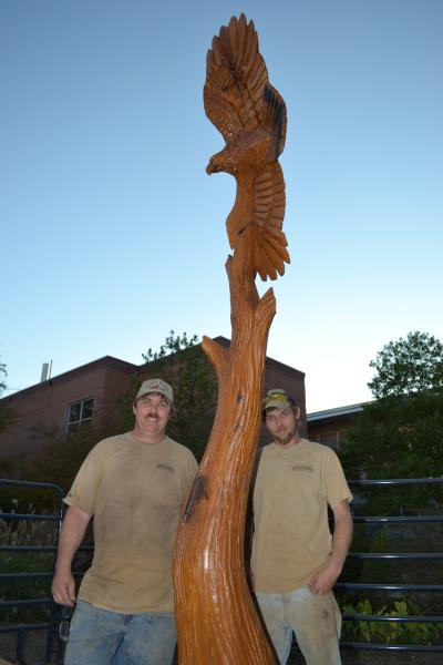 Chainsaw artist Dayton Scoggins, left, and son Kenneth pose with an ailing live oak they transformed into a golden eagle on the Southern Miss Hattiesburg campus.