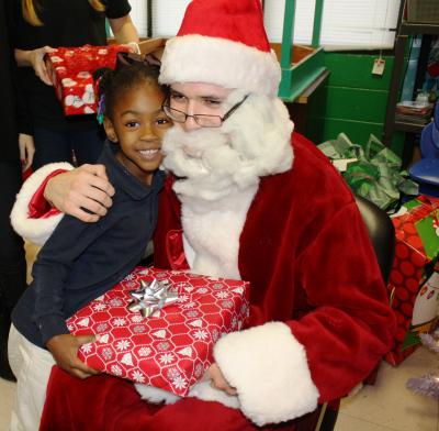 Santa Claus, played by Southern Miss Honors College student Robert Williamson, hugs Aniyah Price after giving her a Christmas present Dec. 7 during a holiday party thrown by the college for children who participate in the Aldersgate Mission's after-school programming. (University Communications photo by David Tisdale)