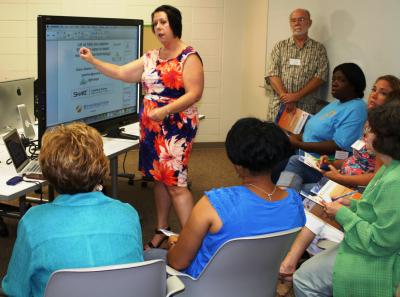 Grace Strahan, center, a training manager with Synergetics DCS Inc., talks with participants in a special education technology workshop for teachers of students with special needs about the advantages of using a SMART Board in their classroom. The workshop was held June 28 at the Southern Miss Hattiesburg campus. (University Communications photo by David Tisdale)  
