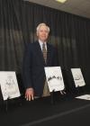 Ralph Dunagin poses with a collection of his original cartoons.