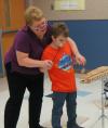 Dr. Mandi Schlegel helps a DuBard student play an instrument.