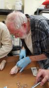 Senior Research Scientist Jim Franks practices suture techniques on a pig foot.