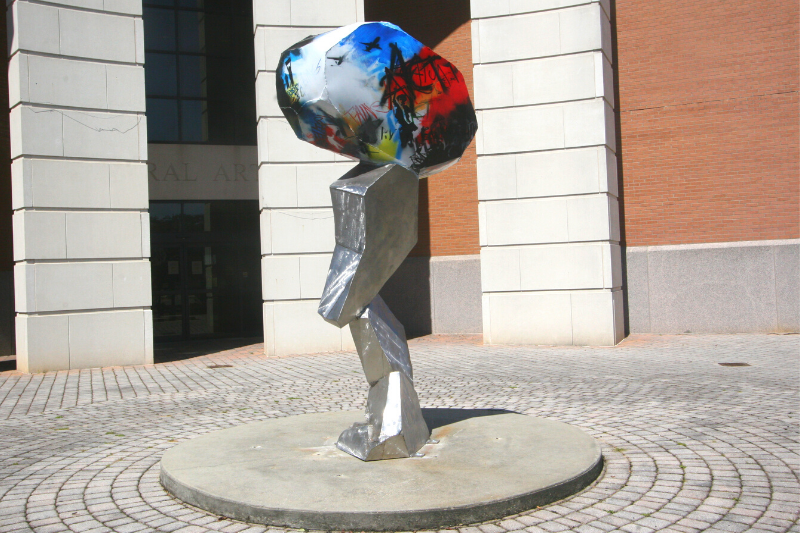 A 2021 USM Outdoor Sculpture featuring silver metal and installed on a brick plaze outside the USM Liberal Arts Building