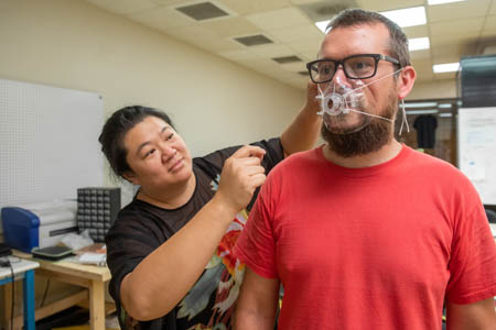 Wan sizes a respirator mask on a colleague in 2020