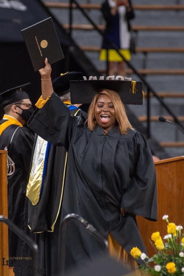 Florence James in cap and gown walking across the stage at graduation
