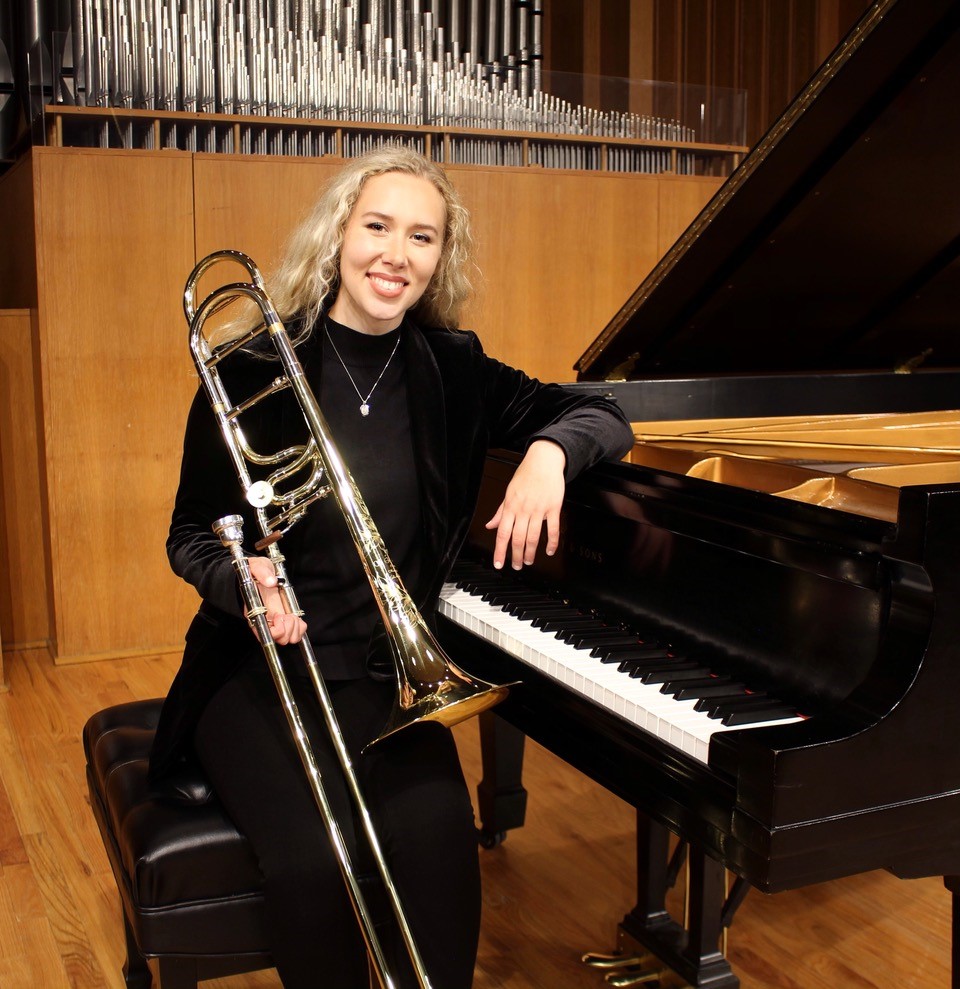 Julianna Hinton sitting at a piano with a trumpet