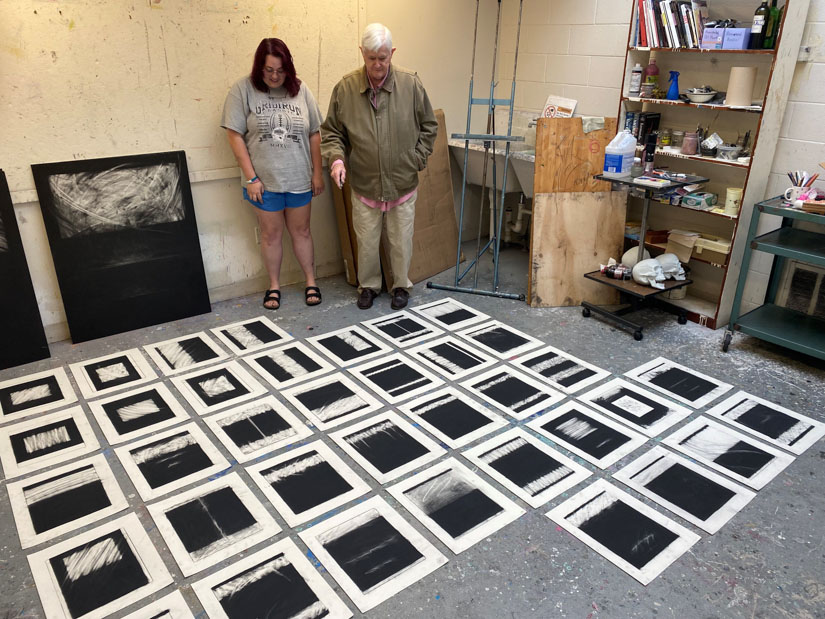 USM Art Professor Jim Meade confers with a USM art student about the collection of compositions she will include in her senior project. 