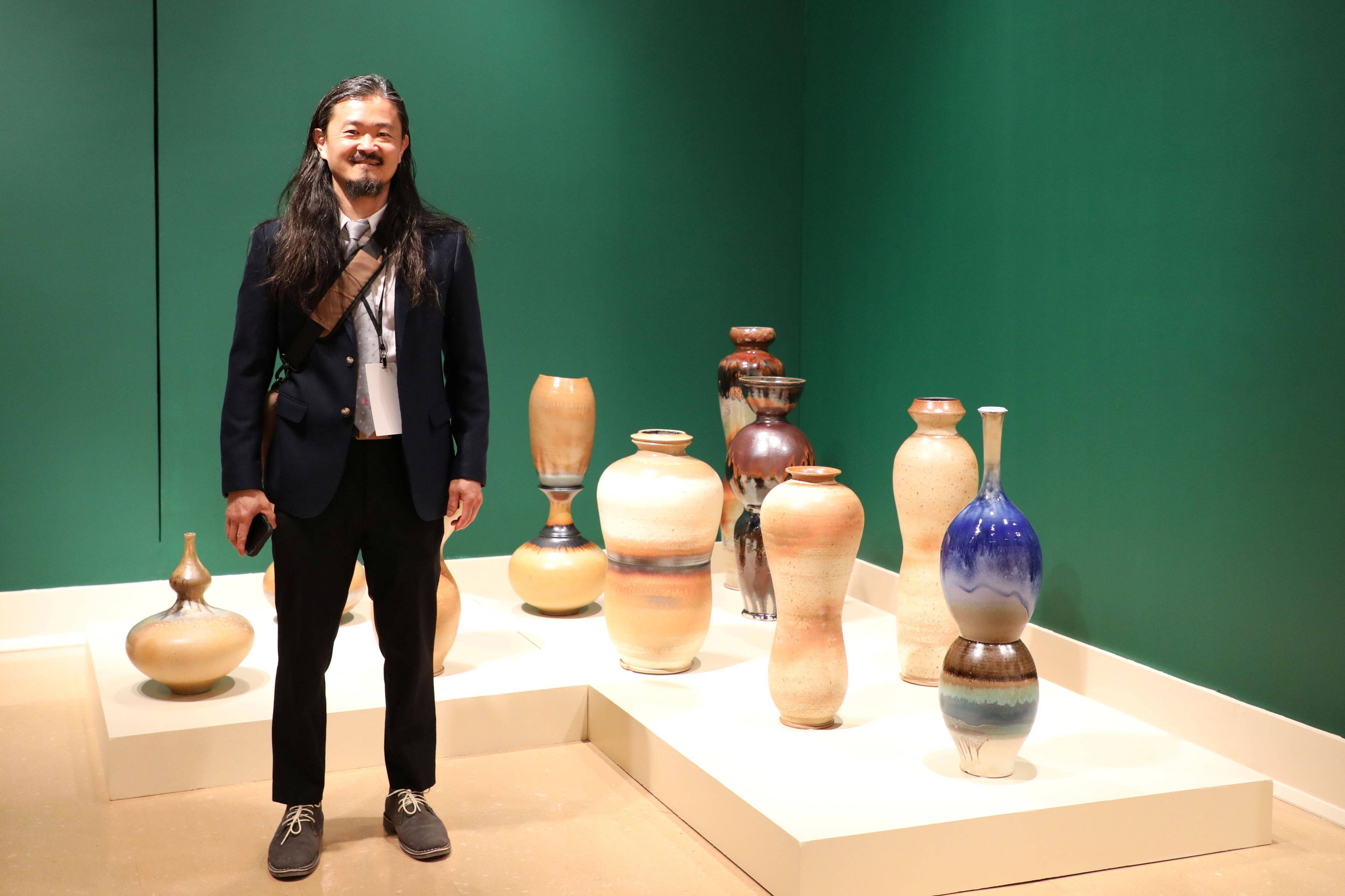 Man standing next to several vases