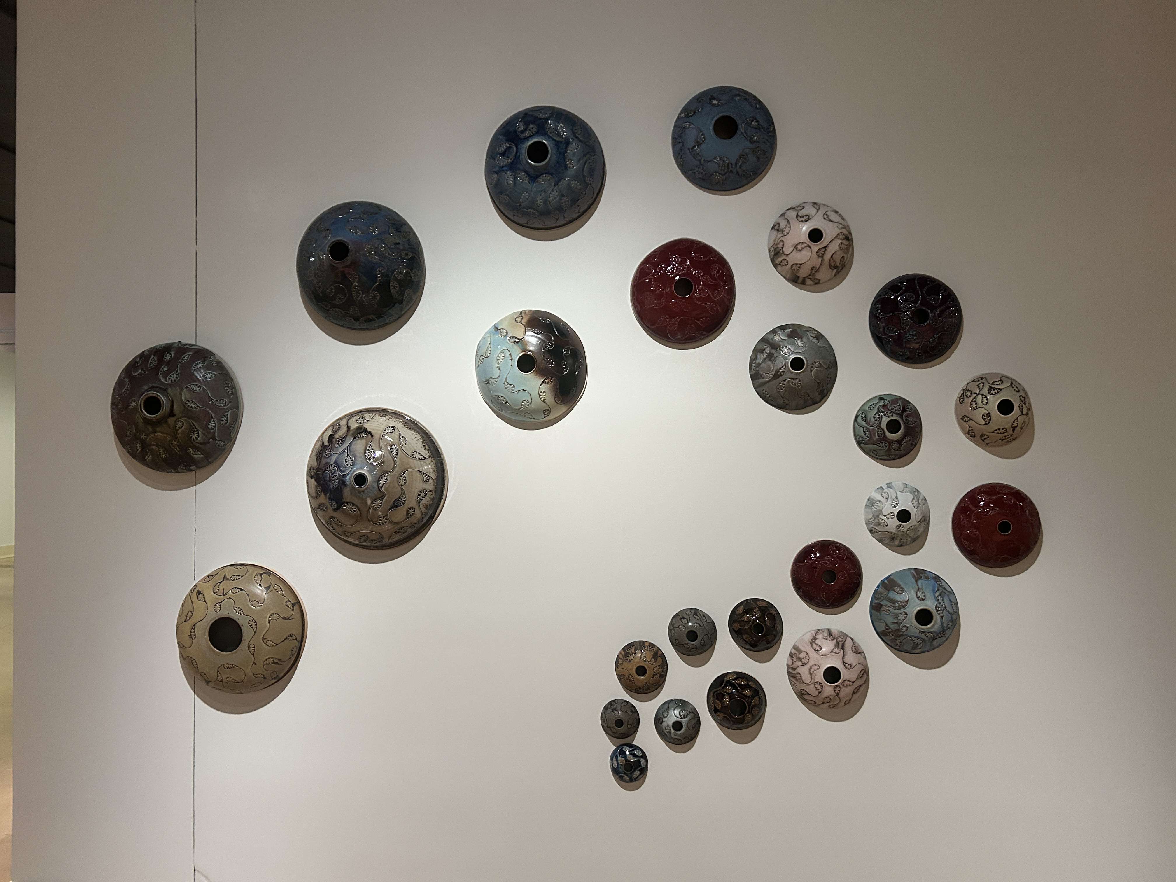 ceramic installation featuring a number of bowls in a spiral pattern on a wall