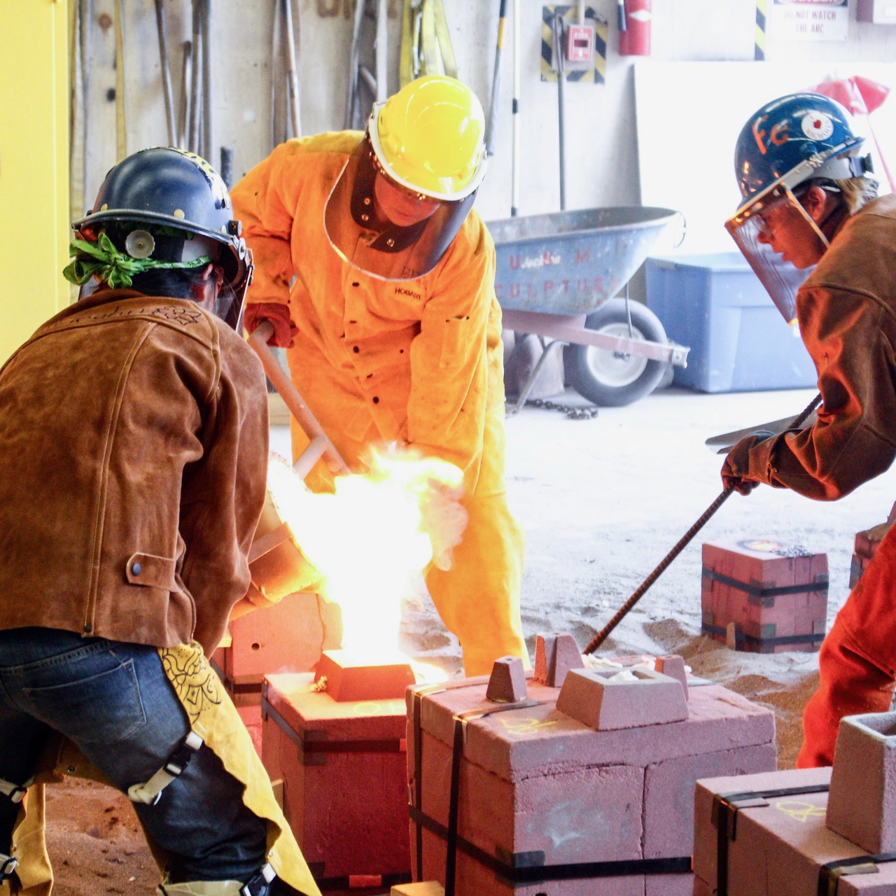 Three people in industrial gear working around a kiln