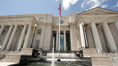 Exterior photo of Trent Lott National Center with American flag and fountain