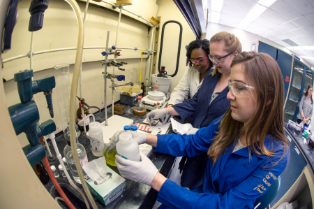 Graduate and undergraduate students work in fume hood