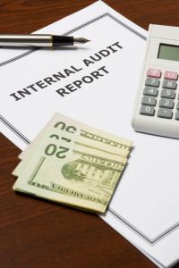 photo of internal audit report, calculator and cash