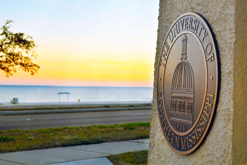 Gulf Park Campus seal in gateway with beach view